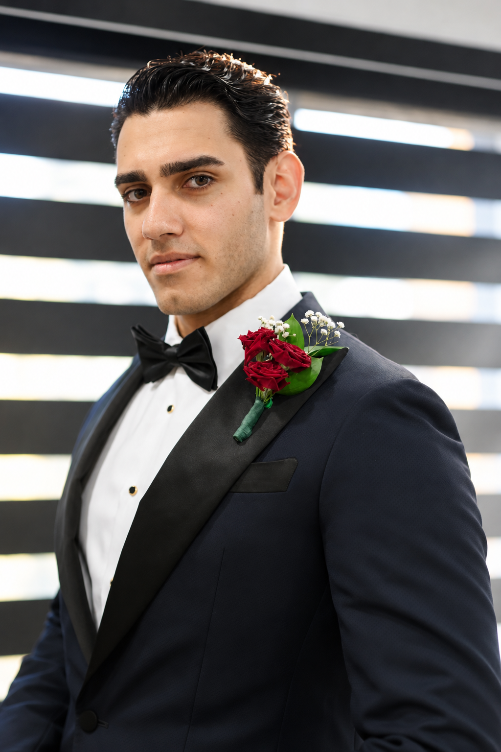 Pouya en smoking avec une boutonnière de roses rouges