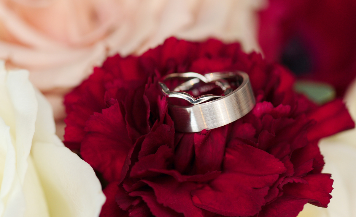 Kristine and Kenneth's wedding rings on a red carnation